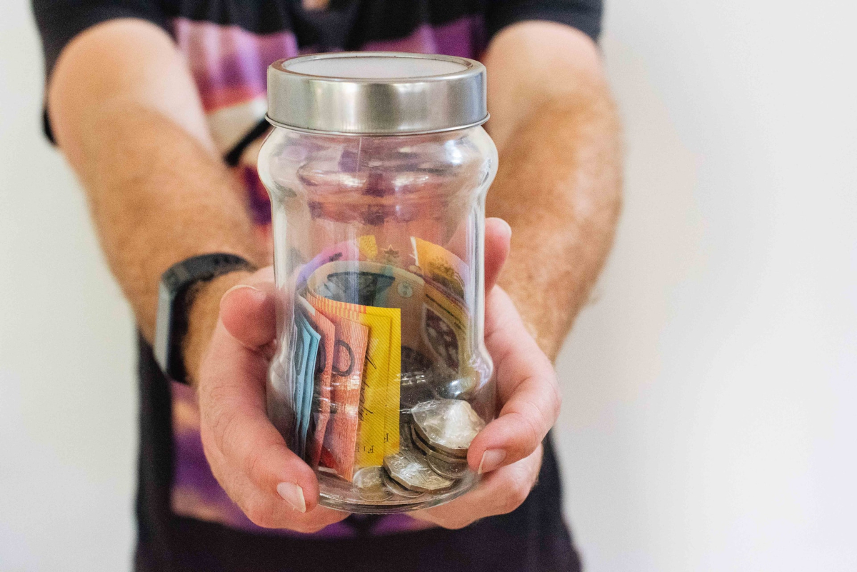 Person holding a jar of Australian money