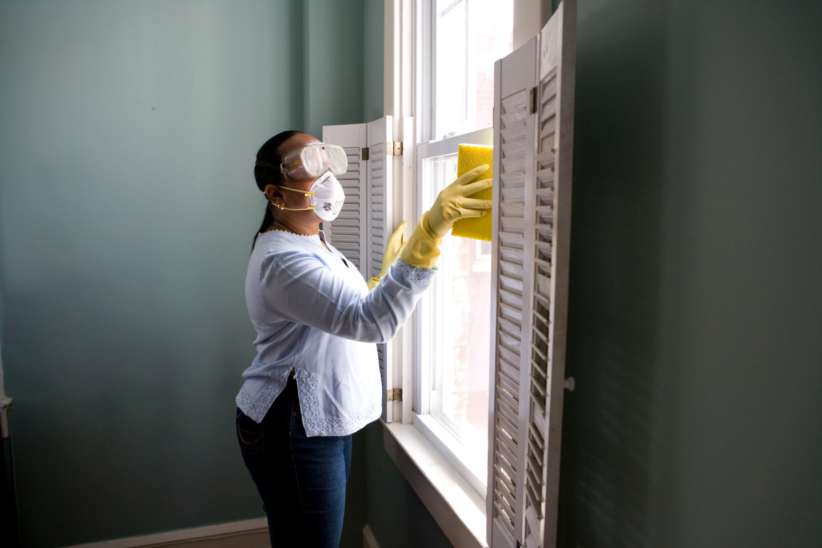 Women cleaning a window dressed in protective equipment